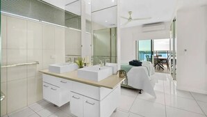 Un baño moderno con dos lavamanos, un espejo grande y un ventilador de techo.