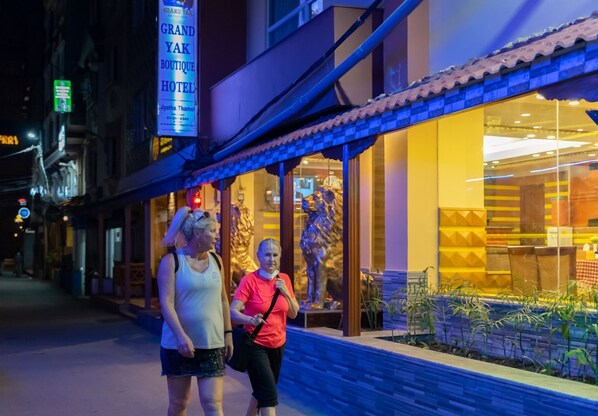 A hotel with a sign reading "Grand Yak Boutique Hotel" and a large golden statue outside.