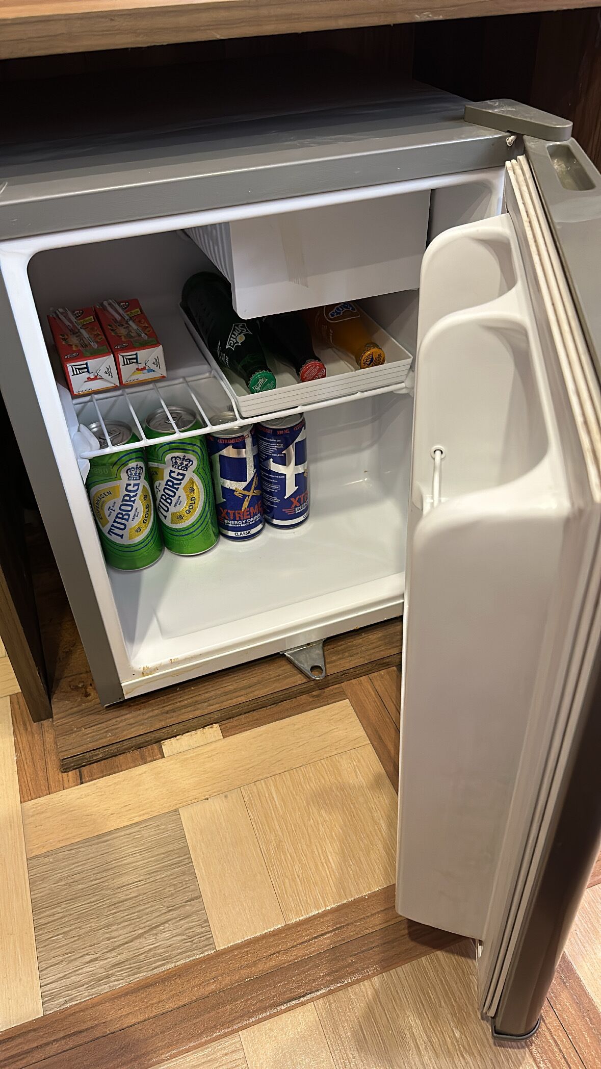 A small refrigerator with a freezer compartment containing various beverages and canned drinks.