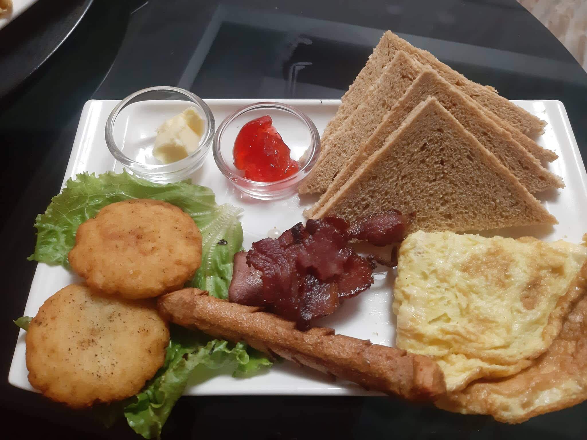 A breakfast plate with toast, eggs, bacon, hash browns, and condiments.