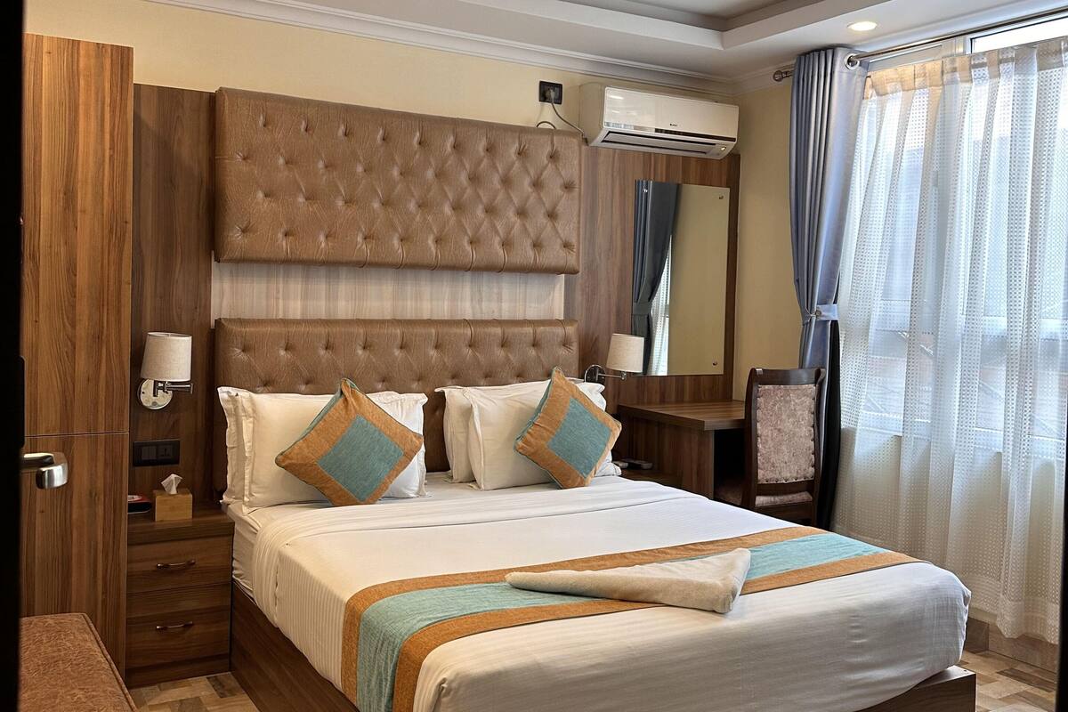 A hotel room with a large bed, wooden headboard, and a ceiling with recessed lighting.