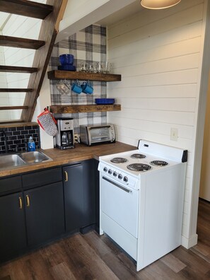 A kitchen with a white stove, black cabinets, a coffee maker, and a toaster. - Sportsman's Landing (Orr)