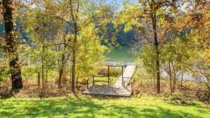 A wooden dock extending into a lake surrounded by trees with autumn foliage.