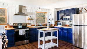 A kitchen with wooden cabinets, a stainless steel stove, a microwave, and a refrigerator.