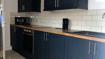A modern kitchen with black cabinets, a microwave, a coffee maker, and a dishwasher.