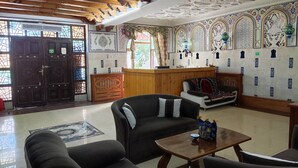 A spacious room with a high wooden ceiling, a reception desk, and a patterned wall.