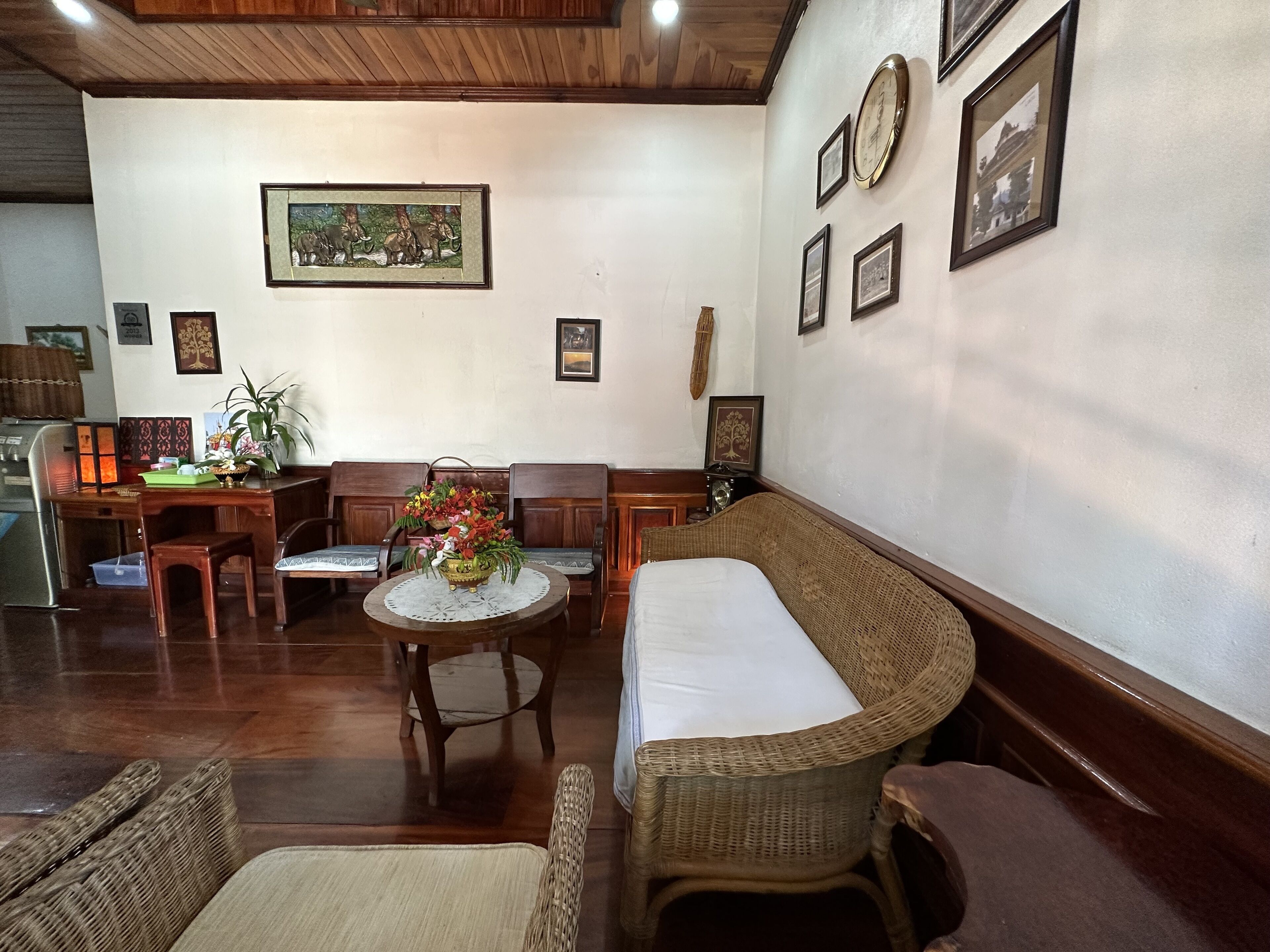 A cozy room with a wooden ceiling, a dining table with chairs, a sofa, and a small round table with a floral centerpiece.