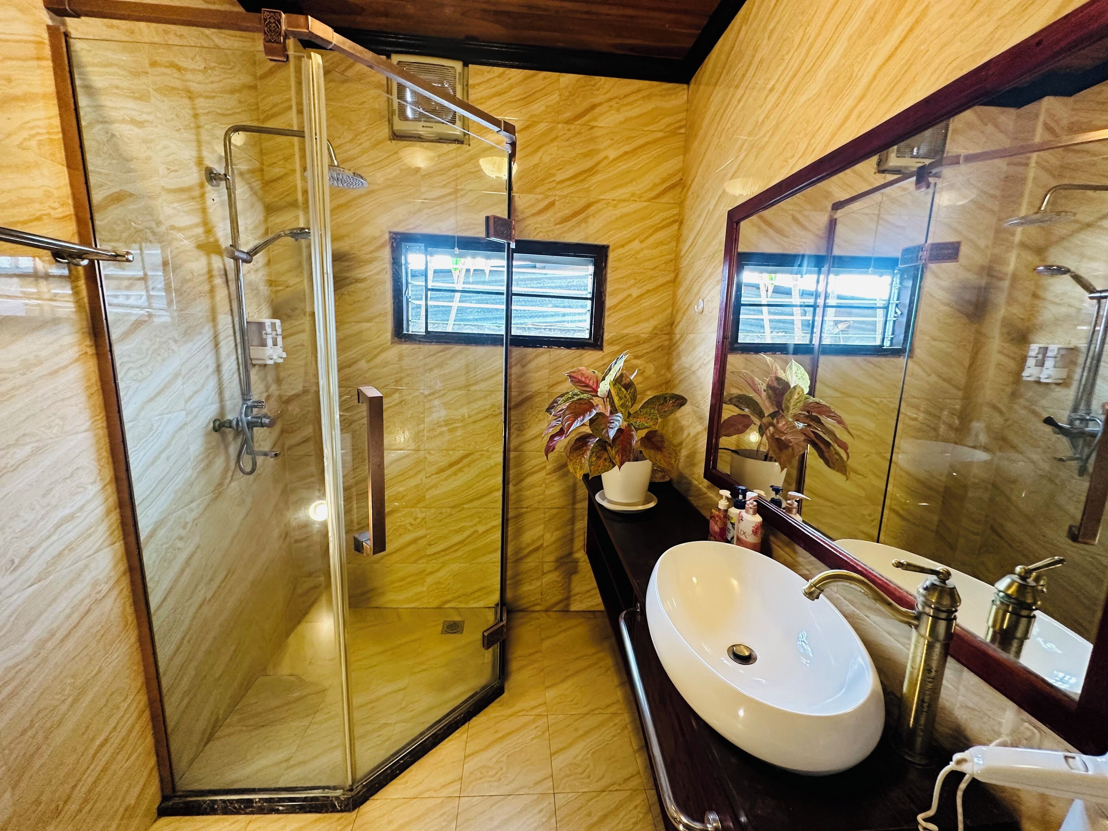 A modern bathroom with a glass-enclosed shower, a white sink, and a large mirror.