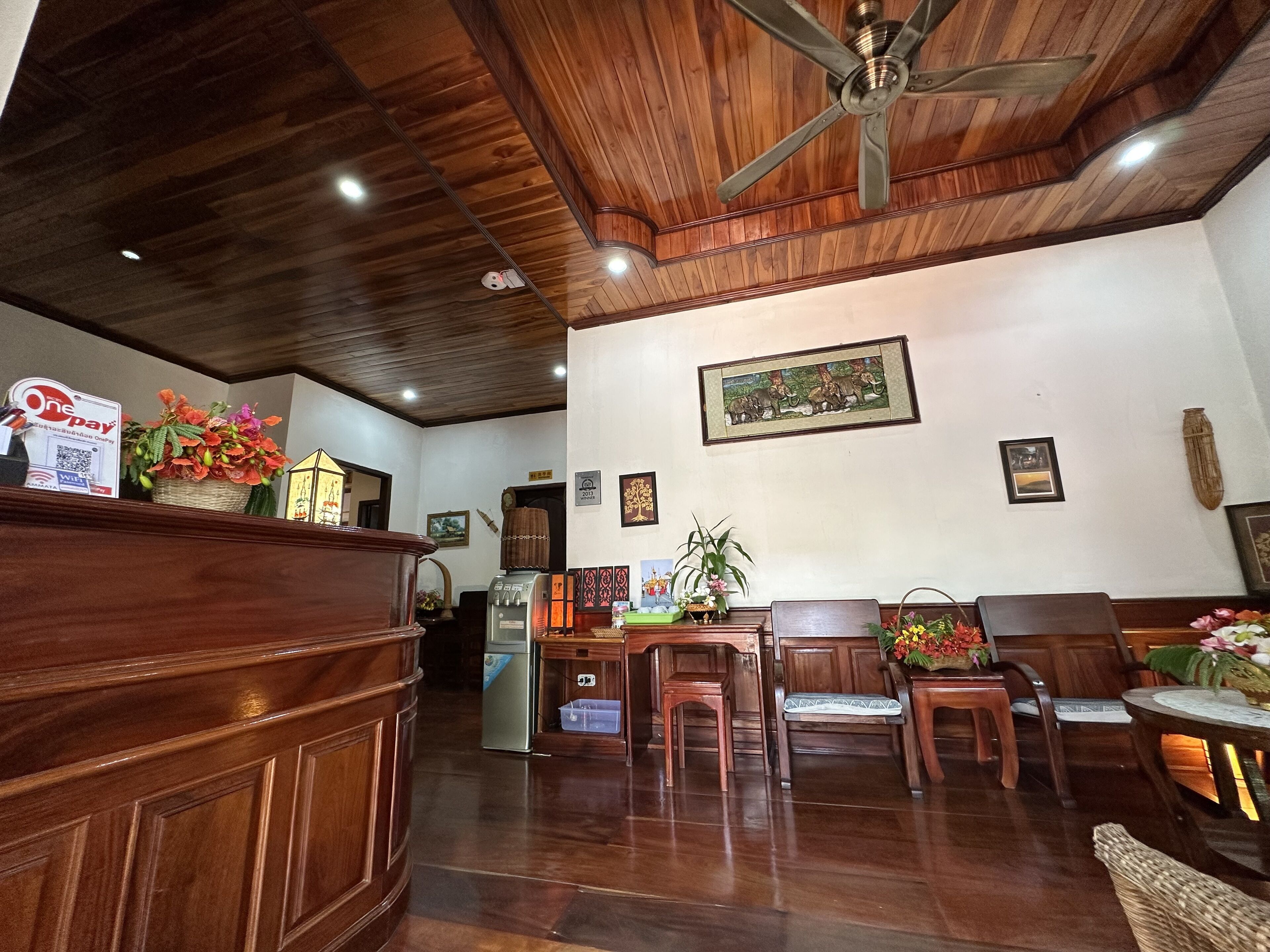 Un mostrador de recepción de madera con un letrero de One Pay, un refrigerador y varias sillas y mesas en un área de recepción.