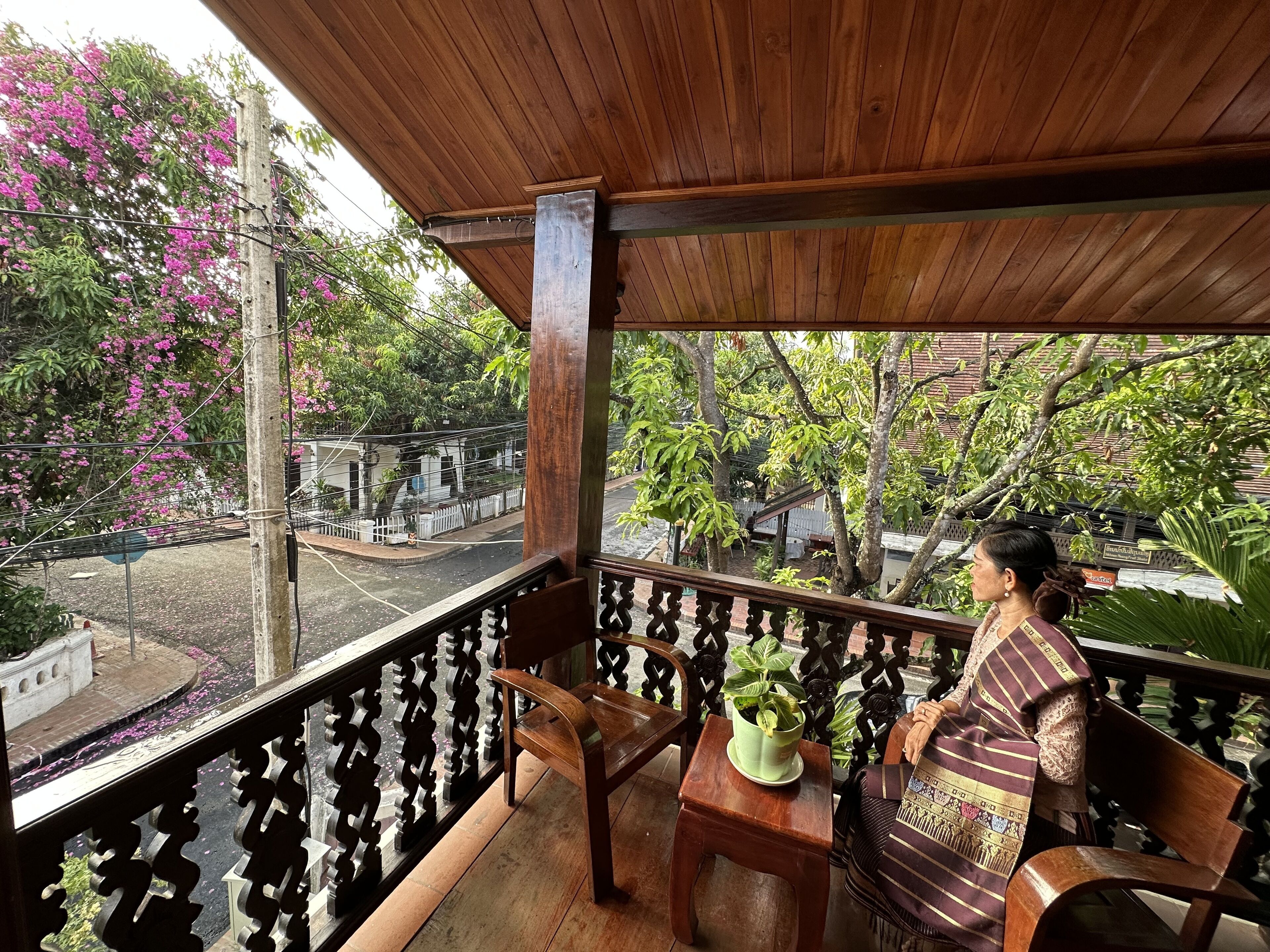 A balcony with a wooden railing, a wooden table, a chair, and a potted plant.