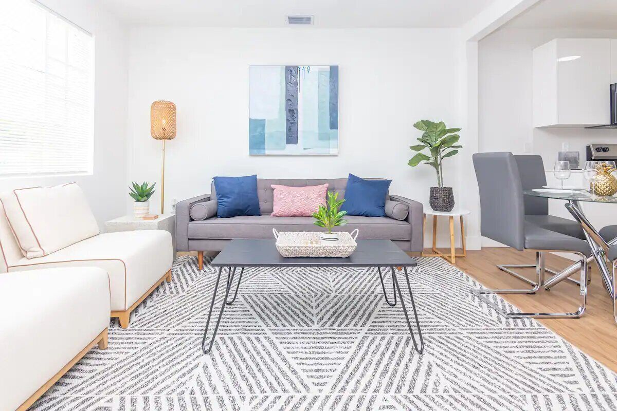 Een moderne woonkamer met een grijze bank, een salontafel, en een eethoek met een stoel en tafel.