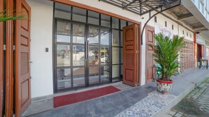 A hotel entrance with a glass door, a red mat, and a potted plant. - Capital O 90447 Kardopa Hotel Megapark (Medan)
