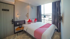 A hotel room with a bed, a small table, a TV, and a balcony with curtains. - Capital O 90447 Kardopa Hotel Megapark (Medan)
