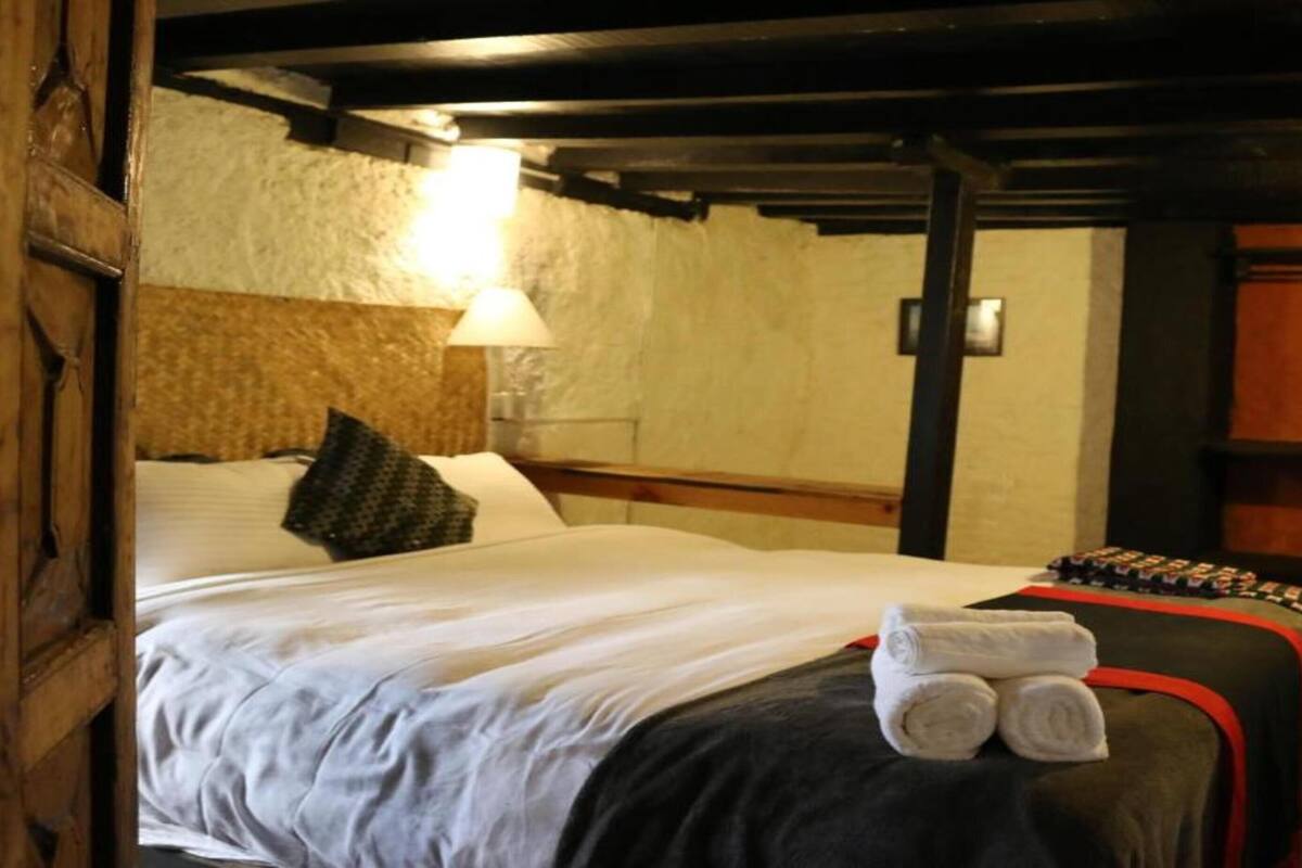 A hotel room with a bed, a lamp, and a set of towels on the bed.