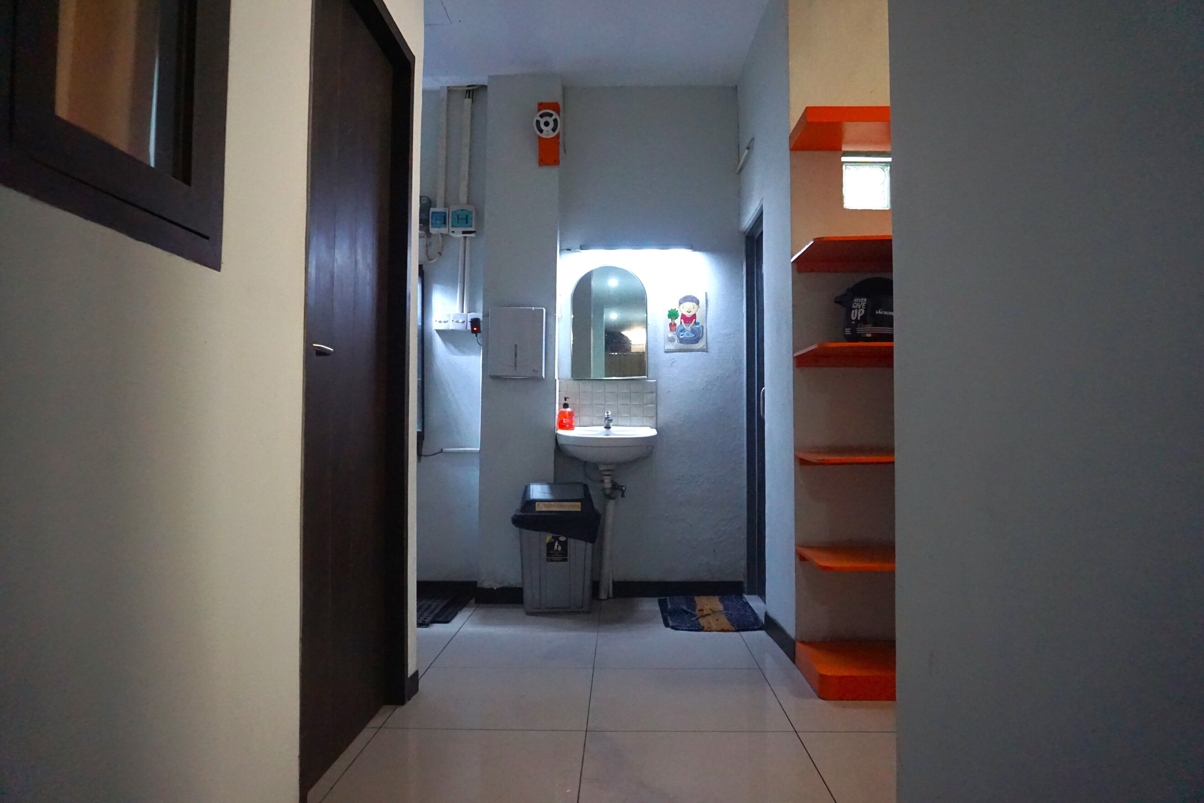 A narrow hallway with a sink, mirror, and shelves.