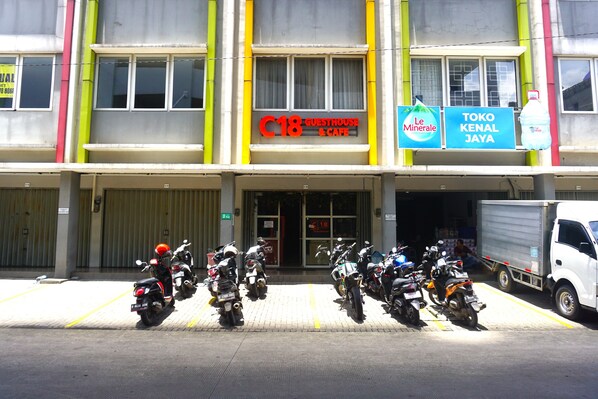 A building with a sign for a guesthouse and cafe, a sign for Le Mineralé, and a sign for Toko Kenal Jaya. - Capital O 3952 Hotel C 18 Cibaduyut (Bandung)