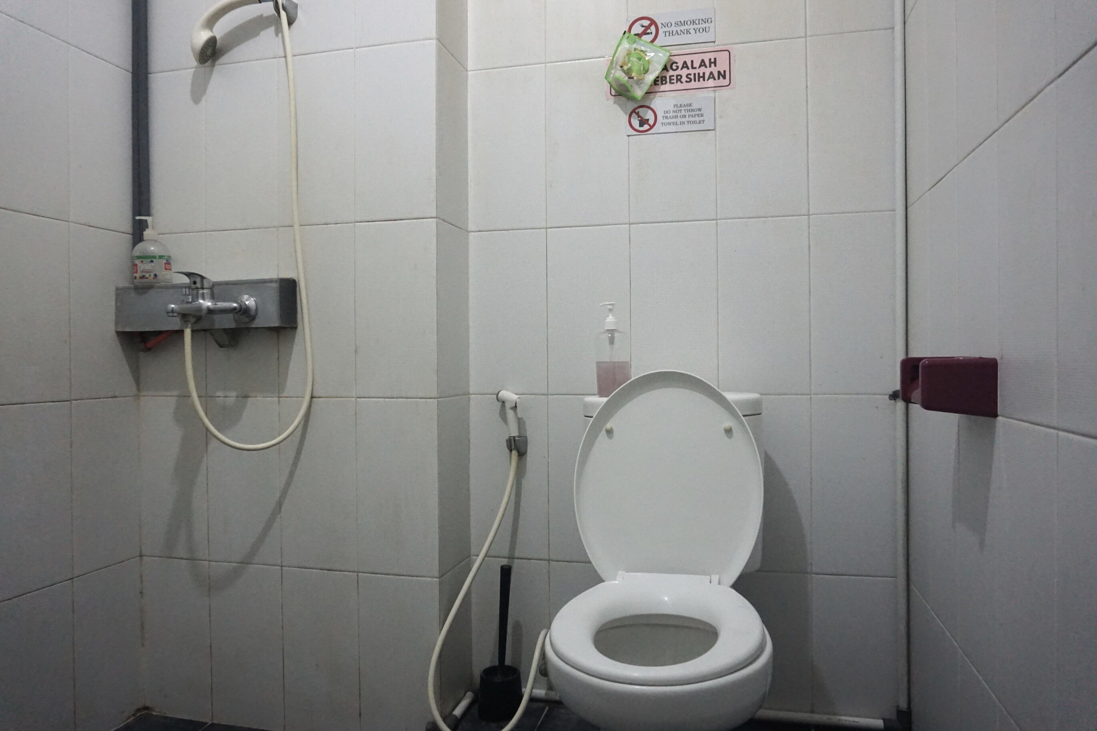 A small, clean bathroom with a toilet, a hand dryer, and a showerhead.