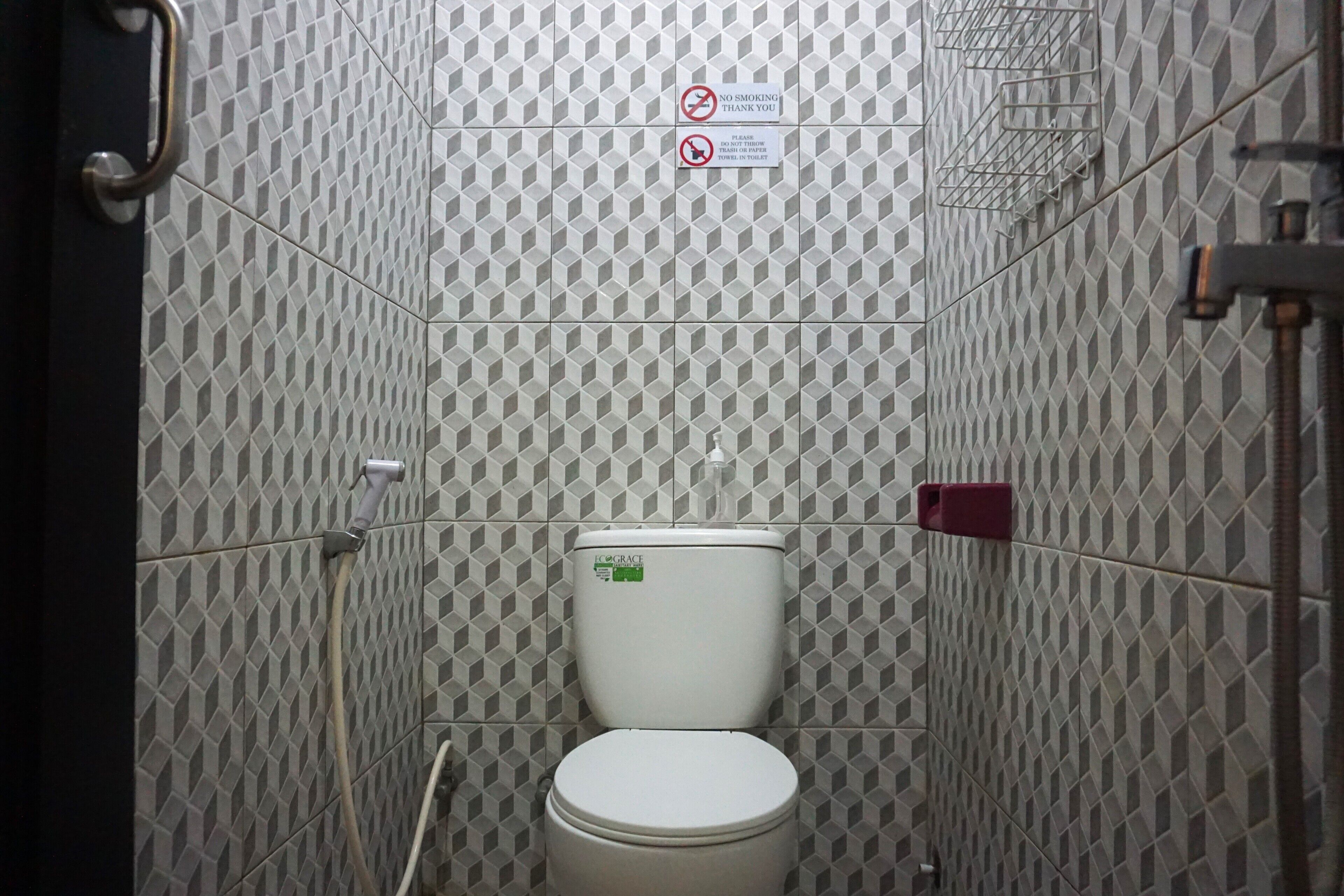 Un baño con inodoro, barandilla y señal de prohibido fumar.