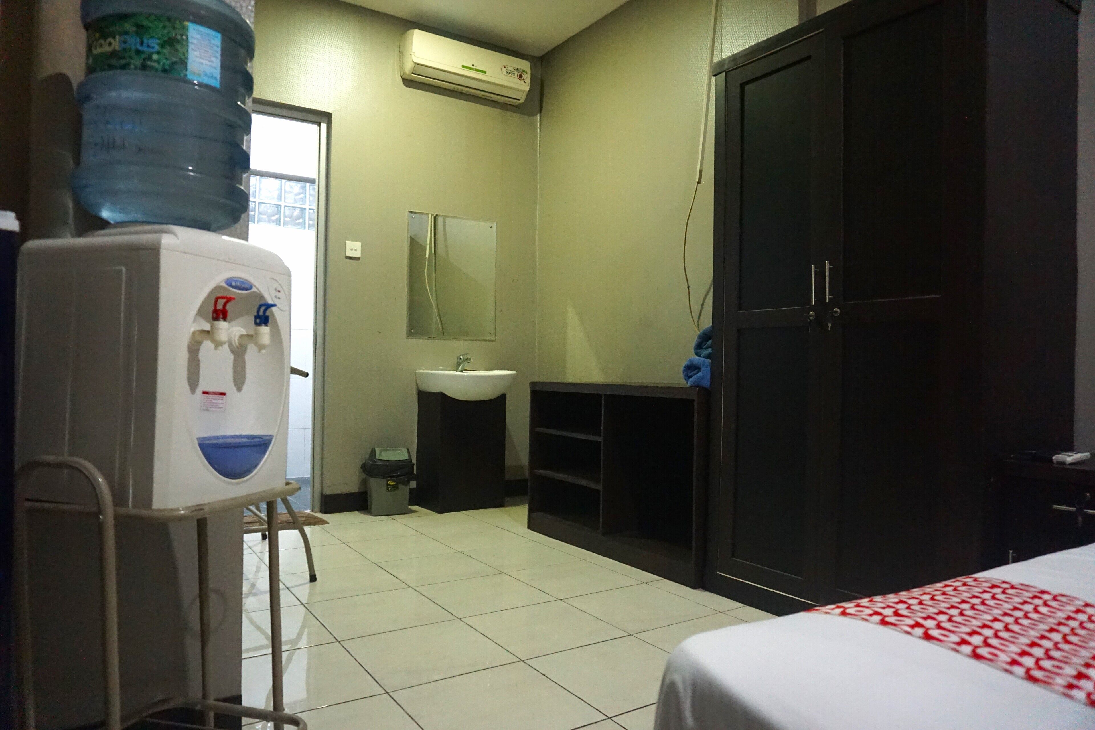 A hotel room with a bed, a water dispenser, a sink, and a wardrobe.