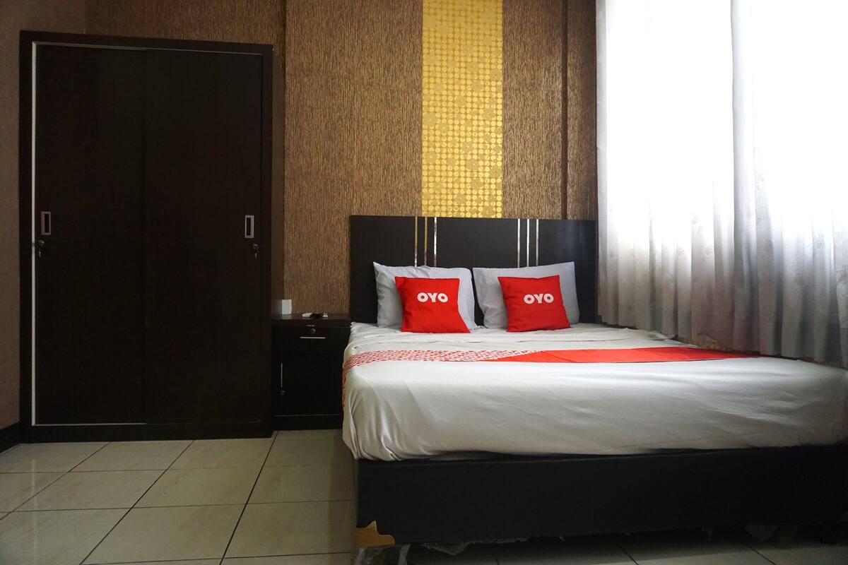 A hotel room with a bed, a wardrobe, and a nightstand.