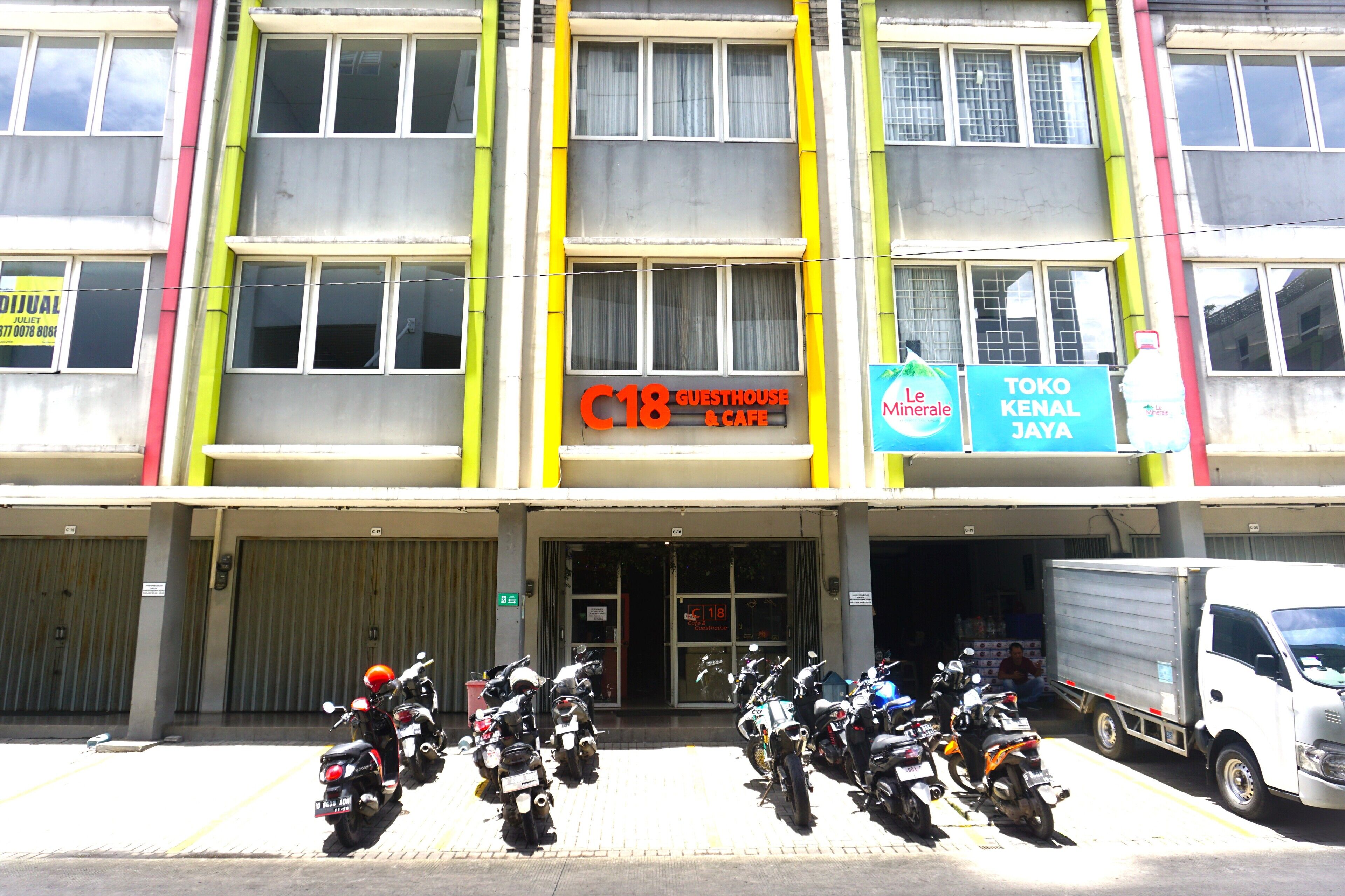 A building with a sign for "C18 Guesthouse & Cafe" and "Toko Kenal Jaya".