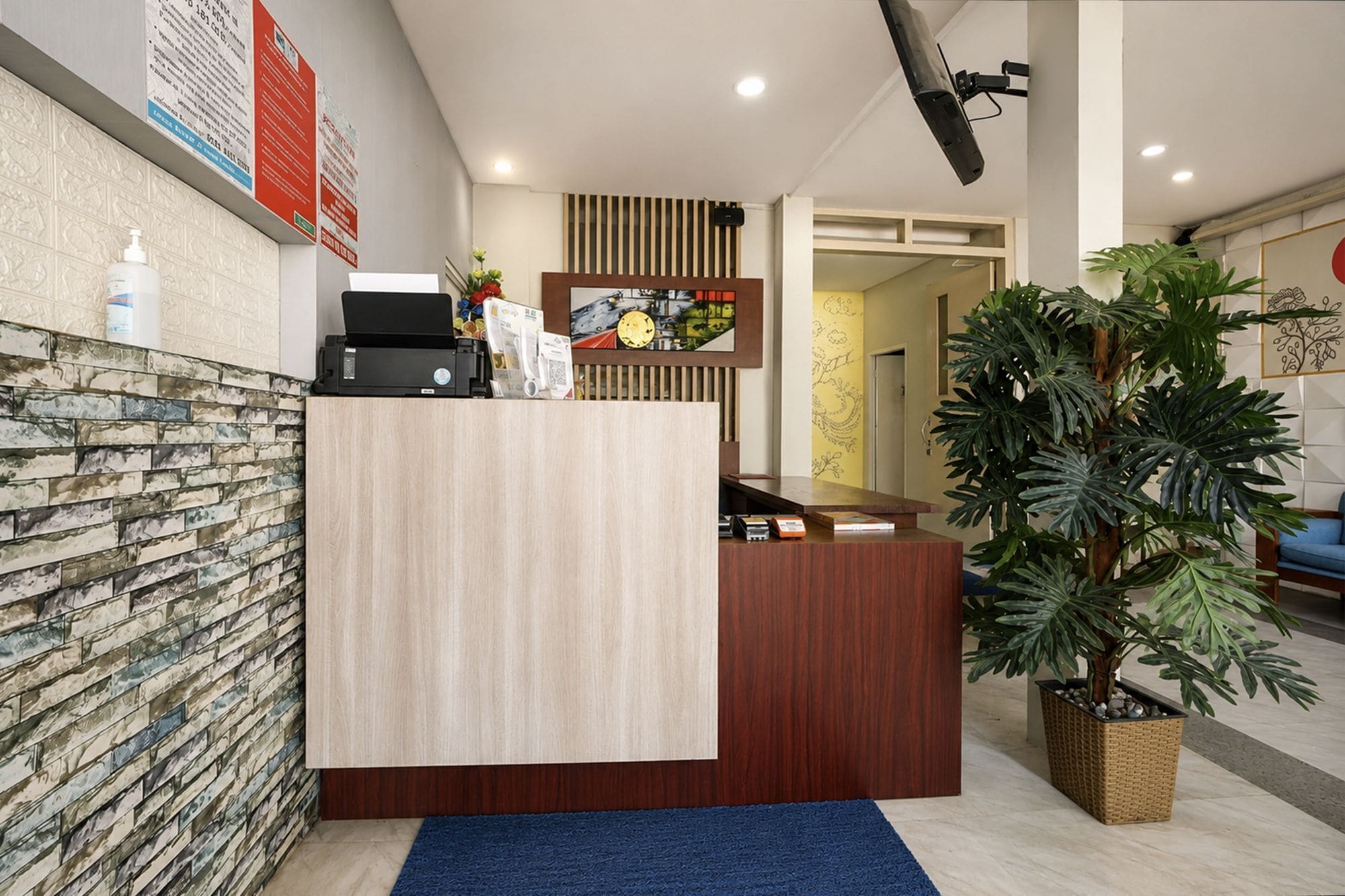 A reception desk with a printer, a plant, and a wall with patterned tiles.