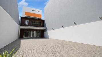 Un edificio moderno con techo plano, amplias ventanas y un patio empedrado.