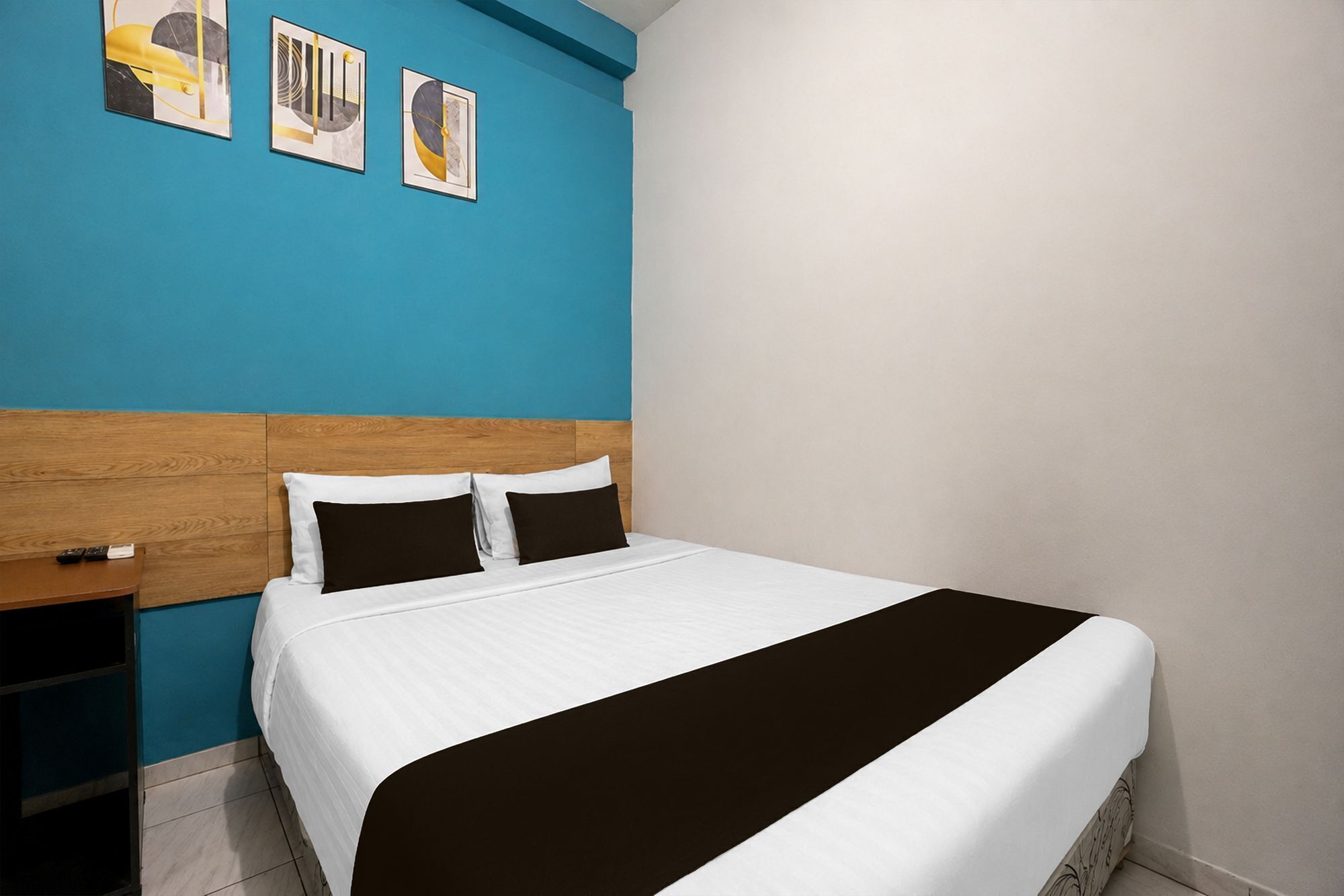 A hotel room with a bed, a nightstand, and a blue accent wall.