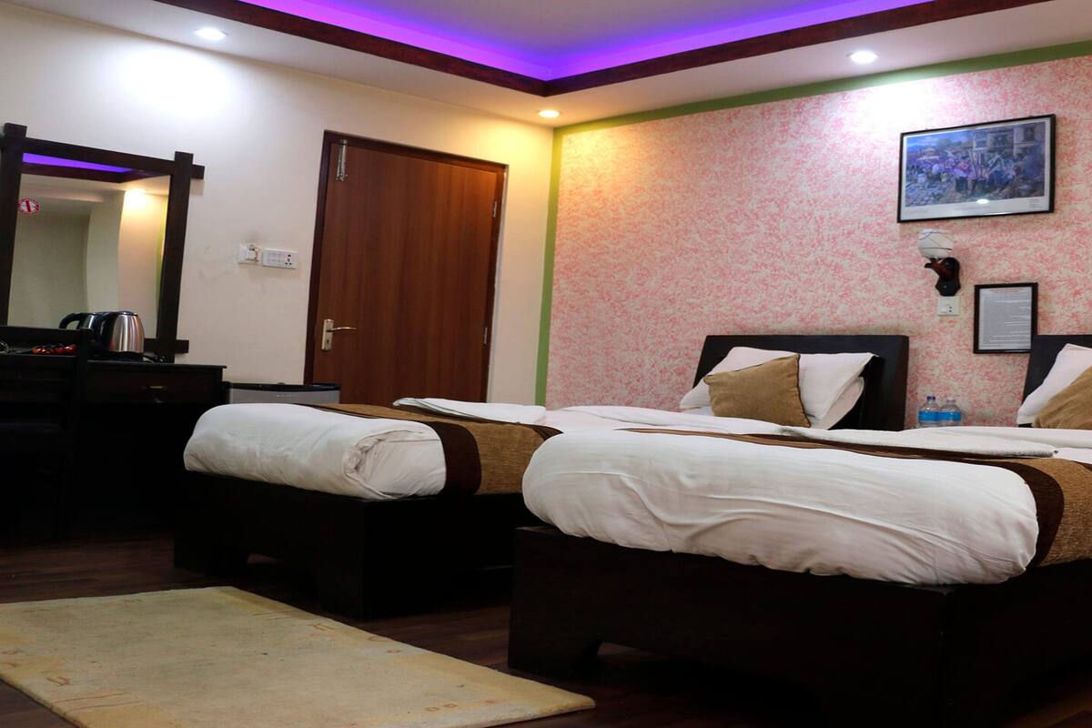A hotel room with two beds, a wooden dresser, a mirror, and a framed picture on the wall.