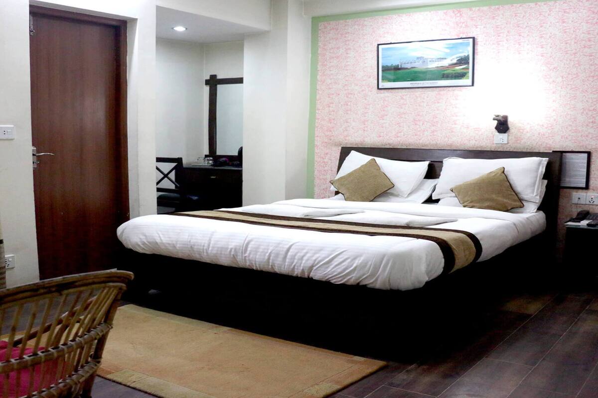 A hotel room with a bed, a desk, a chair, and a picture on the wall.
