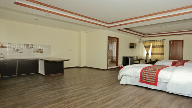 Una habitación de hotel con una cama grande, un escritorio y una kitchenette.