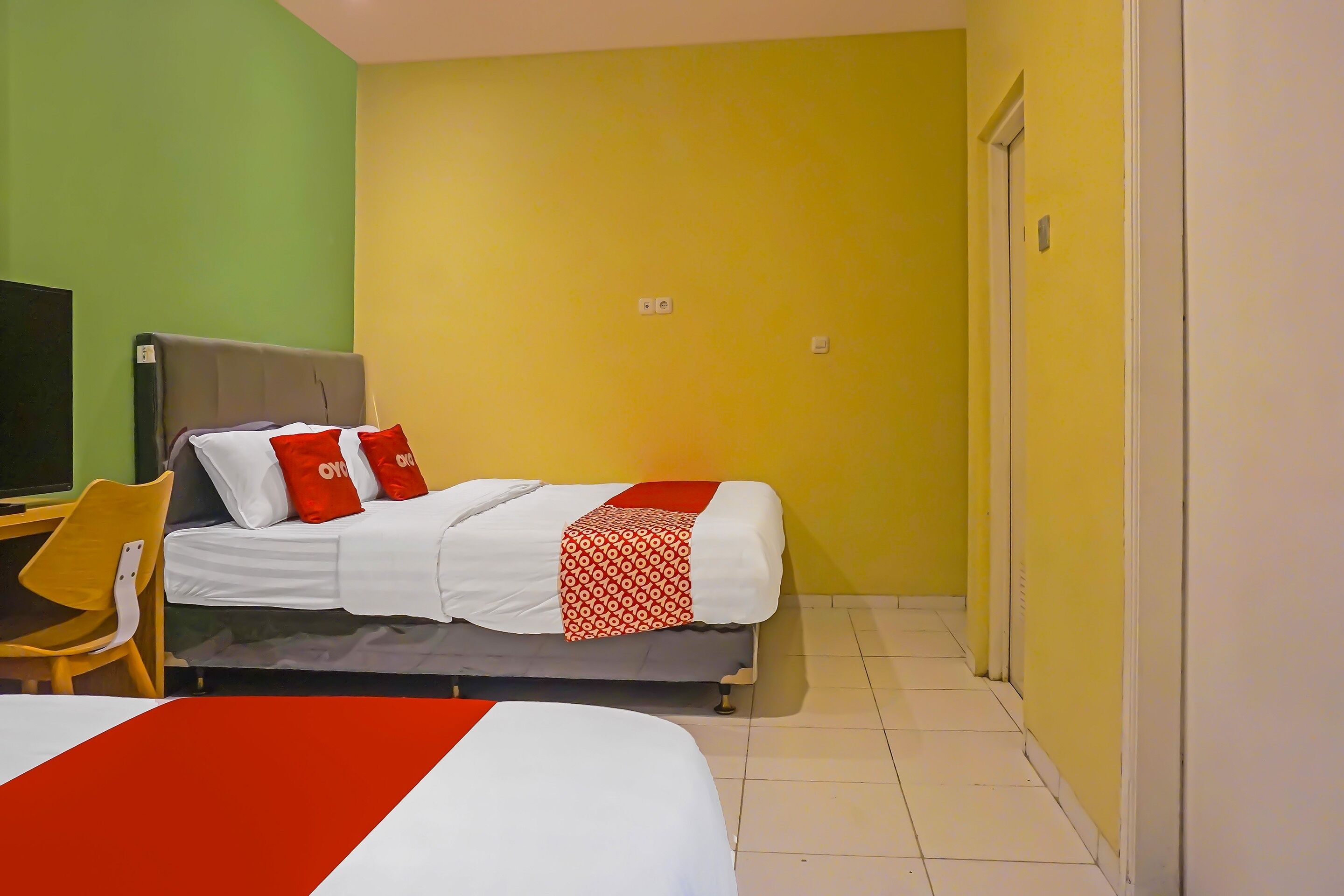 Habitación de hotel con dos camas, televisor y una silla.