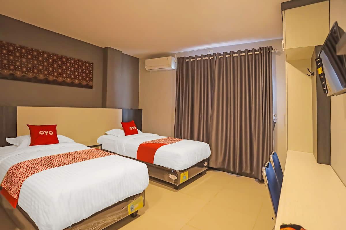 Quarto de hotel com duas camas, televisão e cortina.