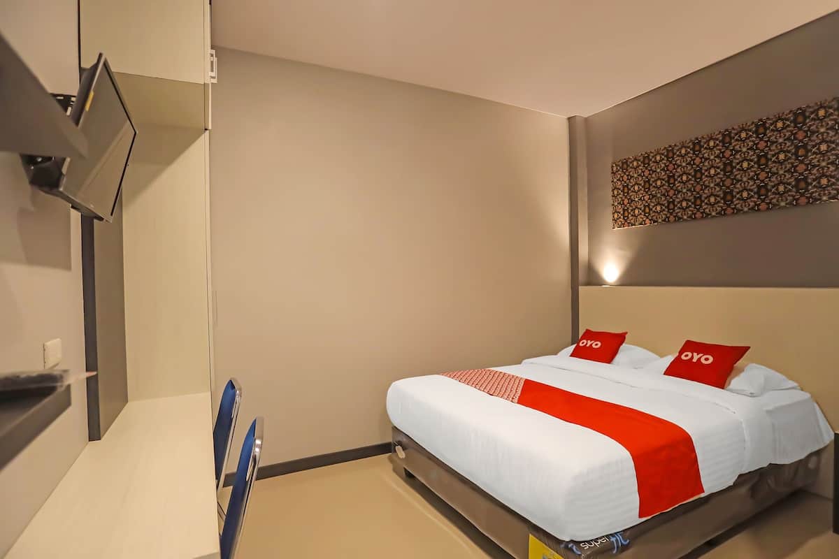 Quarto de hotel com uma cama, uma televisão presa na parede e uma peça decorativa na parede.