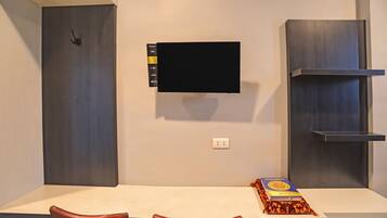 A modern room with a flat-screen TV mounted on the wall, a white table, and two brown chairs.