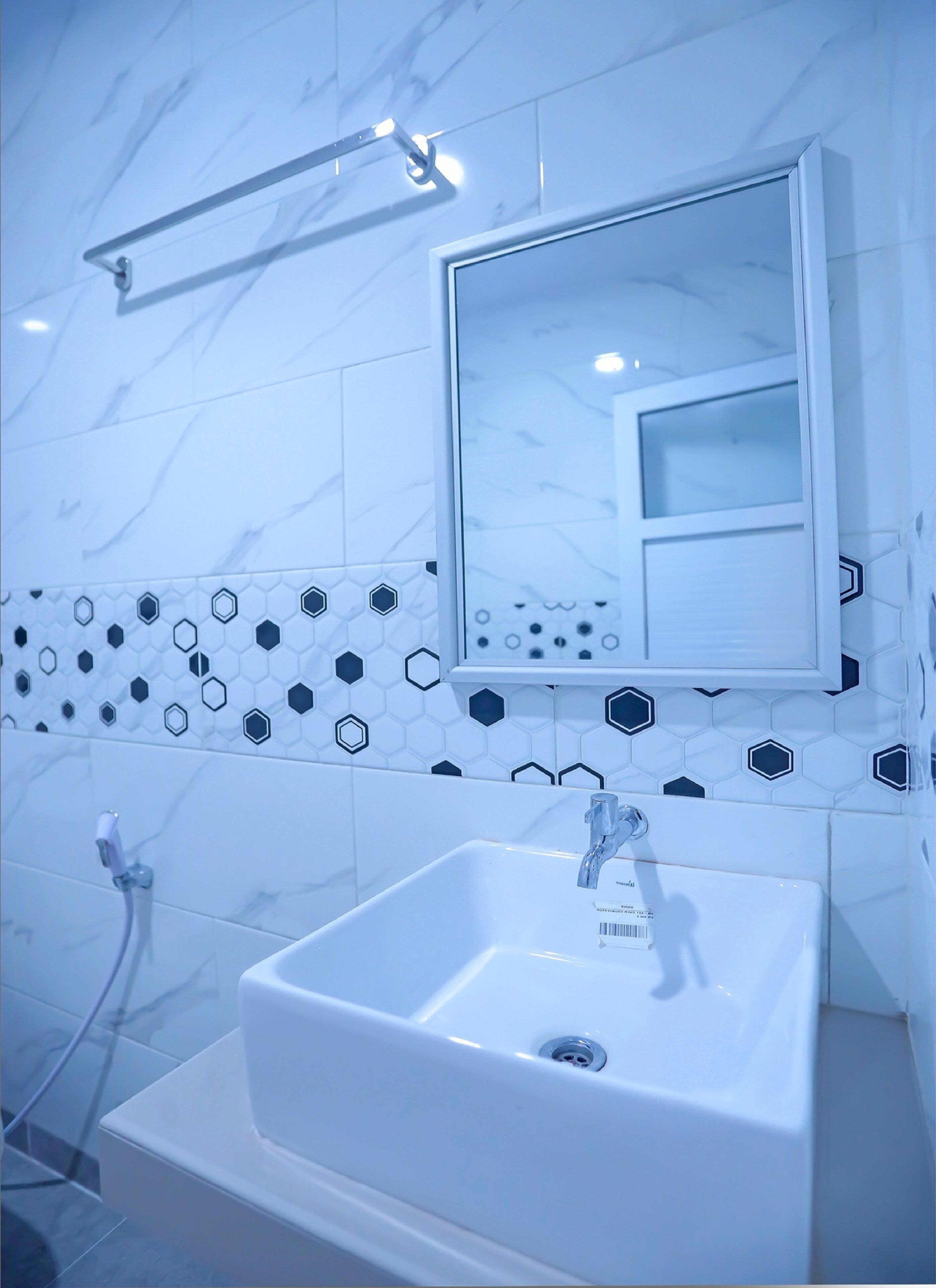 Une salle de bain avec un lavabo blanc, un miroir et un porte-serviettes.