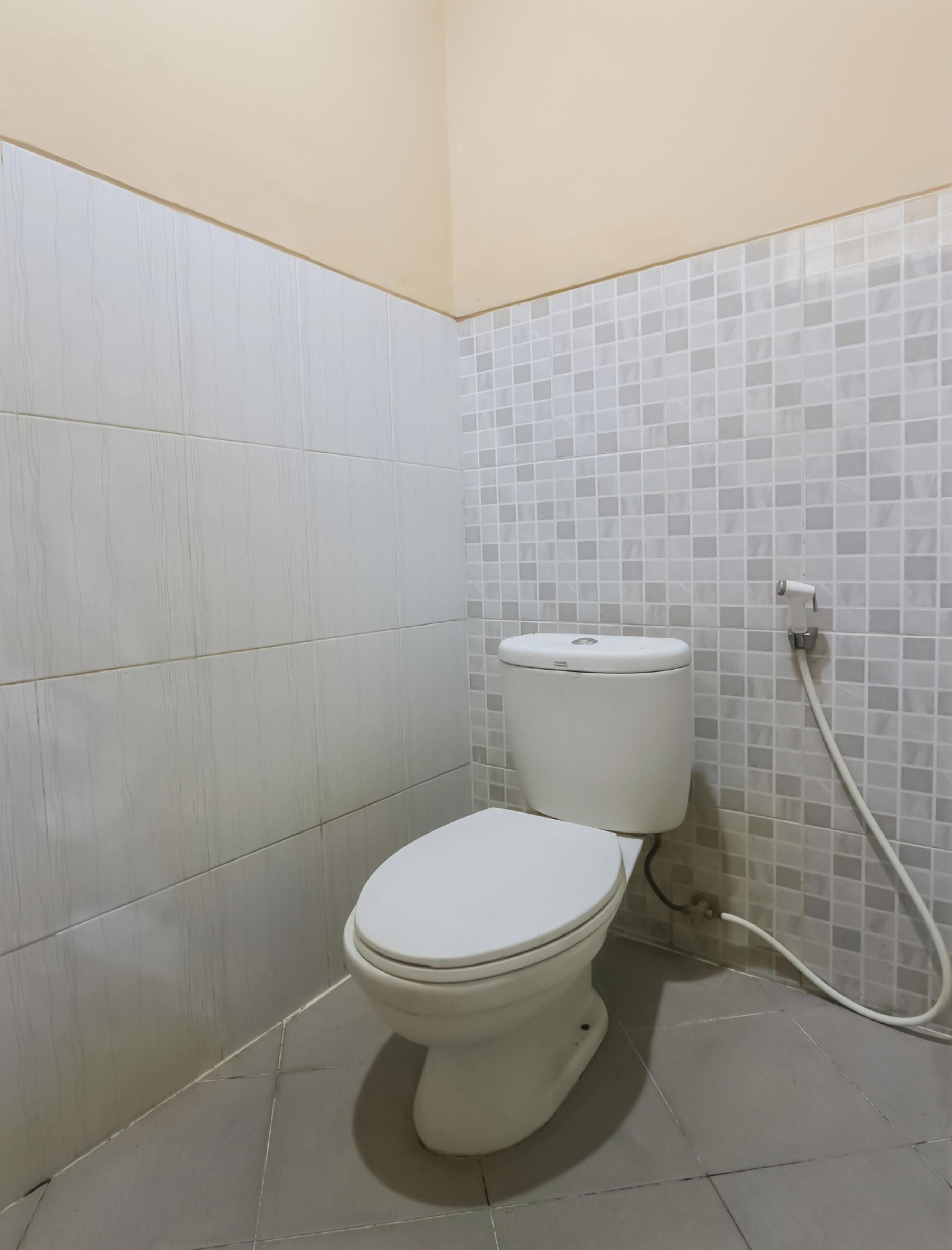 A small bathroom with a toilet, tiled walls, and a tiled floor.