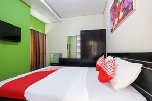 A hotel room with a bed, a flat-screen TV, a wardrobe, and a green wall. - OYO 90193 D'waru Homestay Syariah (Surakarta)