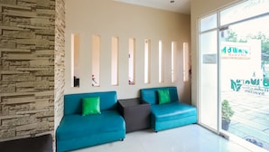 A modern hotel lobby with a stone accent wall, two teal sofas with green cushions, and a large window with a view of the outside.