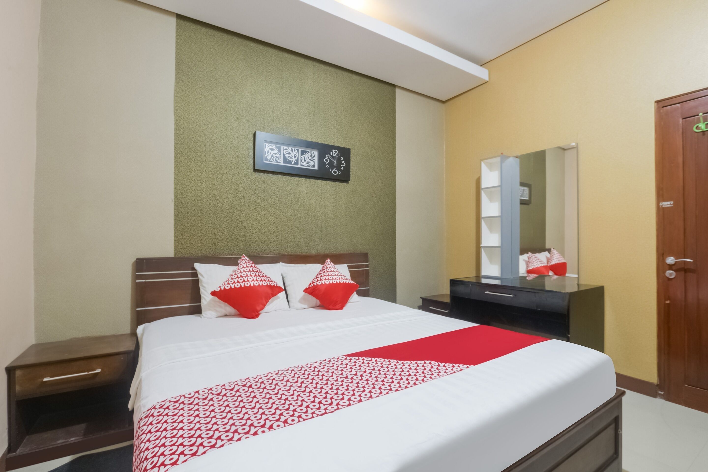 Una habitación de hotel con cama, mesita de noche, cómoda, espejo y puerta.