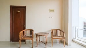 A room with a wooden door labeled '209', two wooden chairs, a small round table, and a white tiled floor.