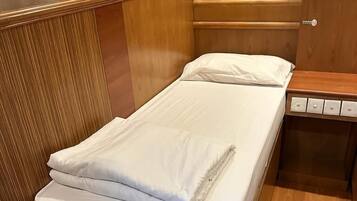 A single bed with white linens in a room with wooden paneling and a tiled wall decoration.