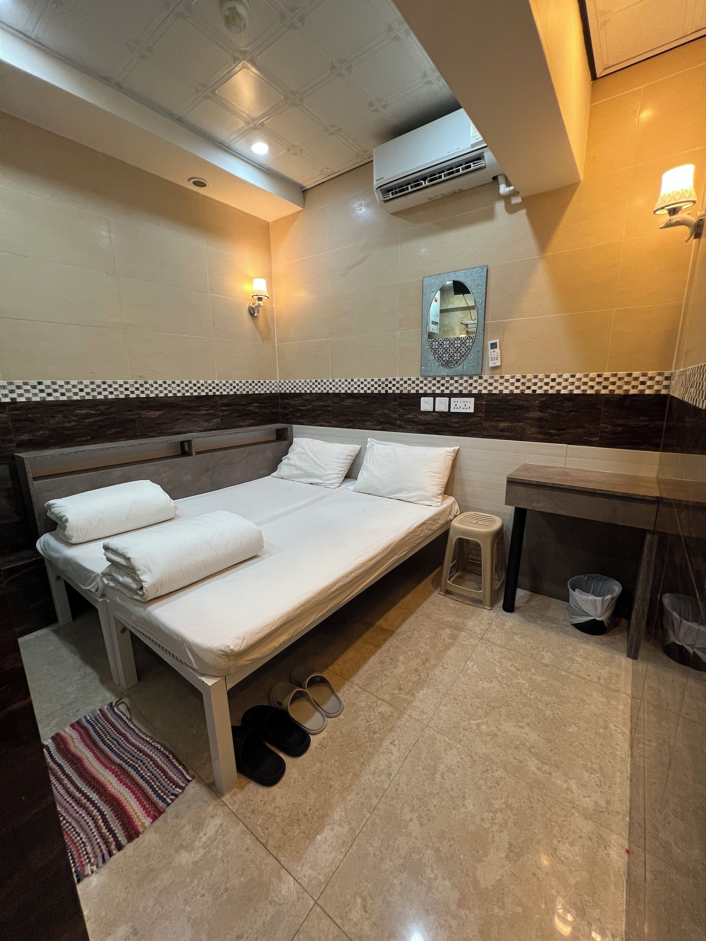 Un dormitorio ordenado con cama, mesita de noche y espejo.