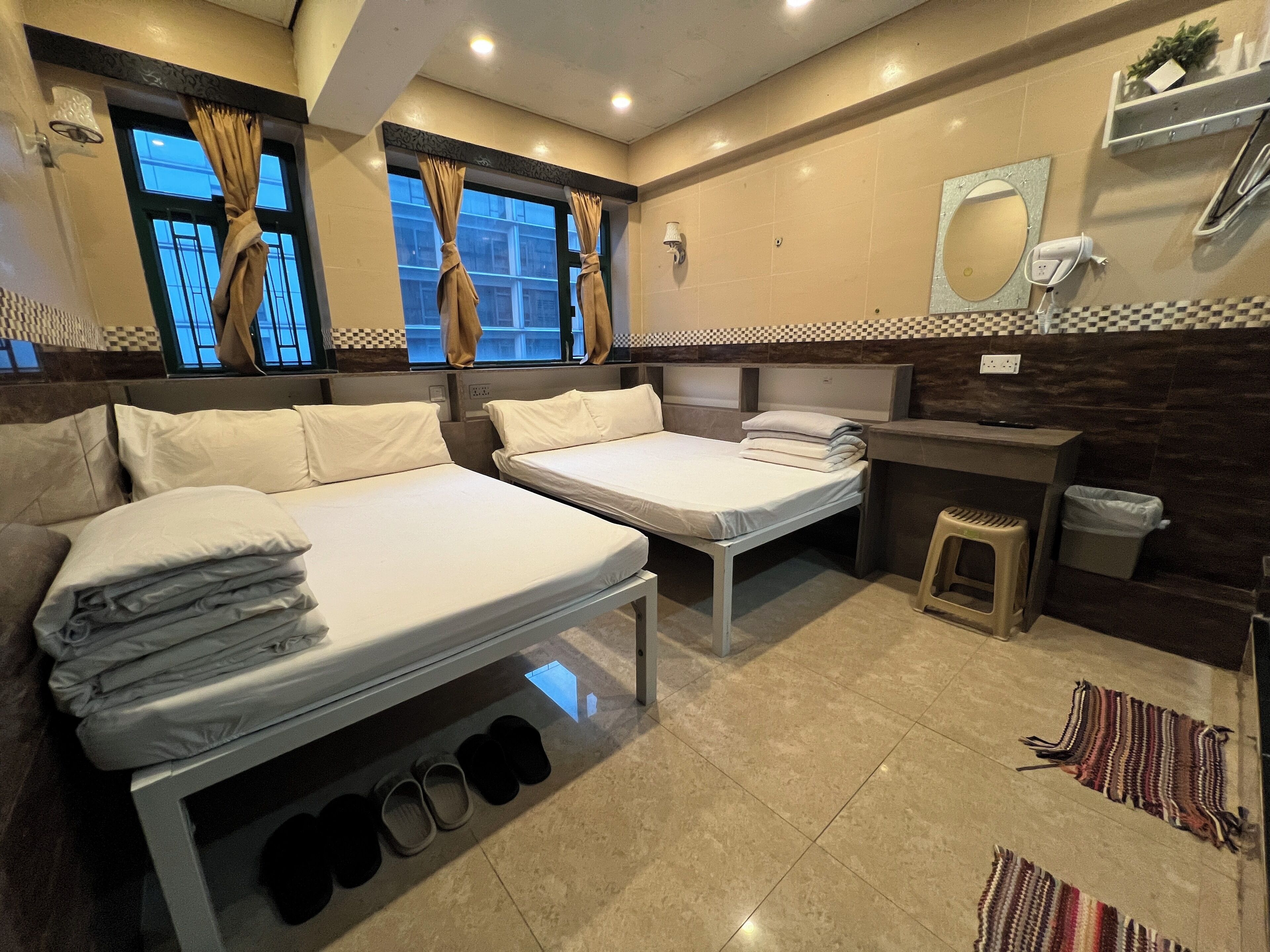 Una habitación de hotel con dos camas, un baño pequeño y un ventanal con cortinas.