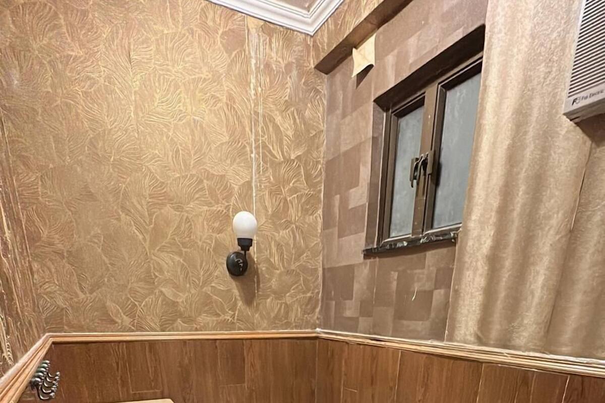 Une petite pièce, de taille modeste, comprenant un lit simple, une armoire en bois et une fenêtre avec des rideaux.