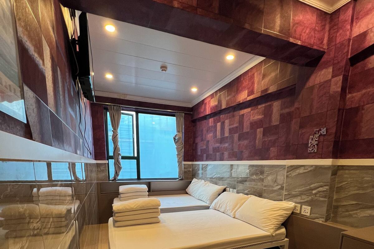 Une chambre moderne avec un grand lit, une tête de lit intégrée et une fenêtre avec des rideaux.