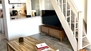 Un espace de vie moderne comprenant un coin cuisine, une table à manger, un canapé et un escalier.