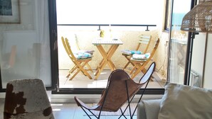 Un salon comprenant un canapé, une table basse agrémentée d’objets décoratifs, un fauteuil pliant et une vue sur un espace extérieur aménagé, visible à travers une porte vitrée.