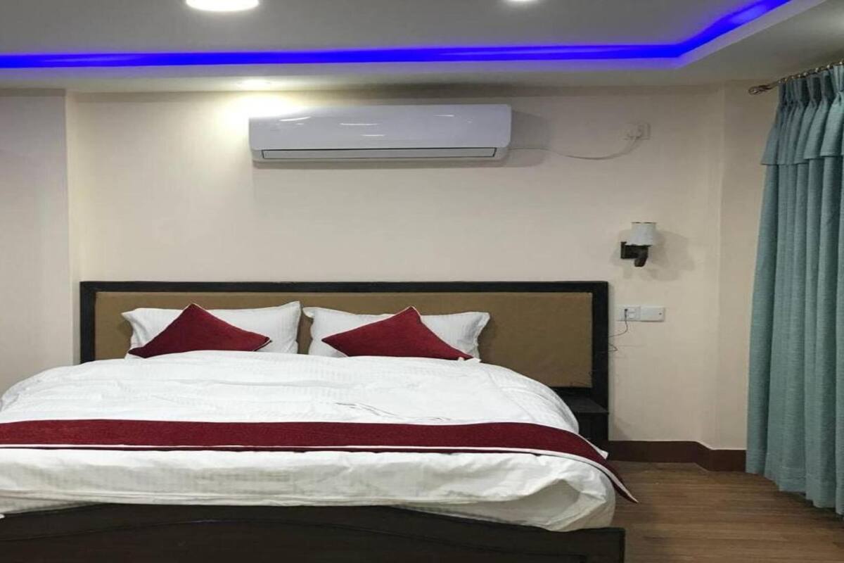 Quarto de hotel com cama, guarda-roupa, ar condicionado e luminária na parede.