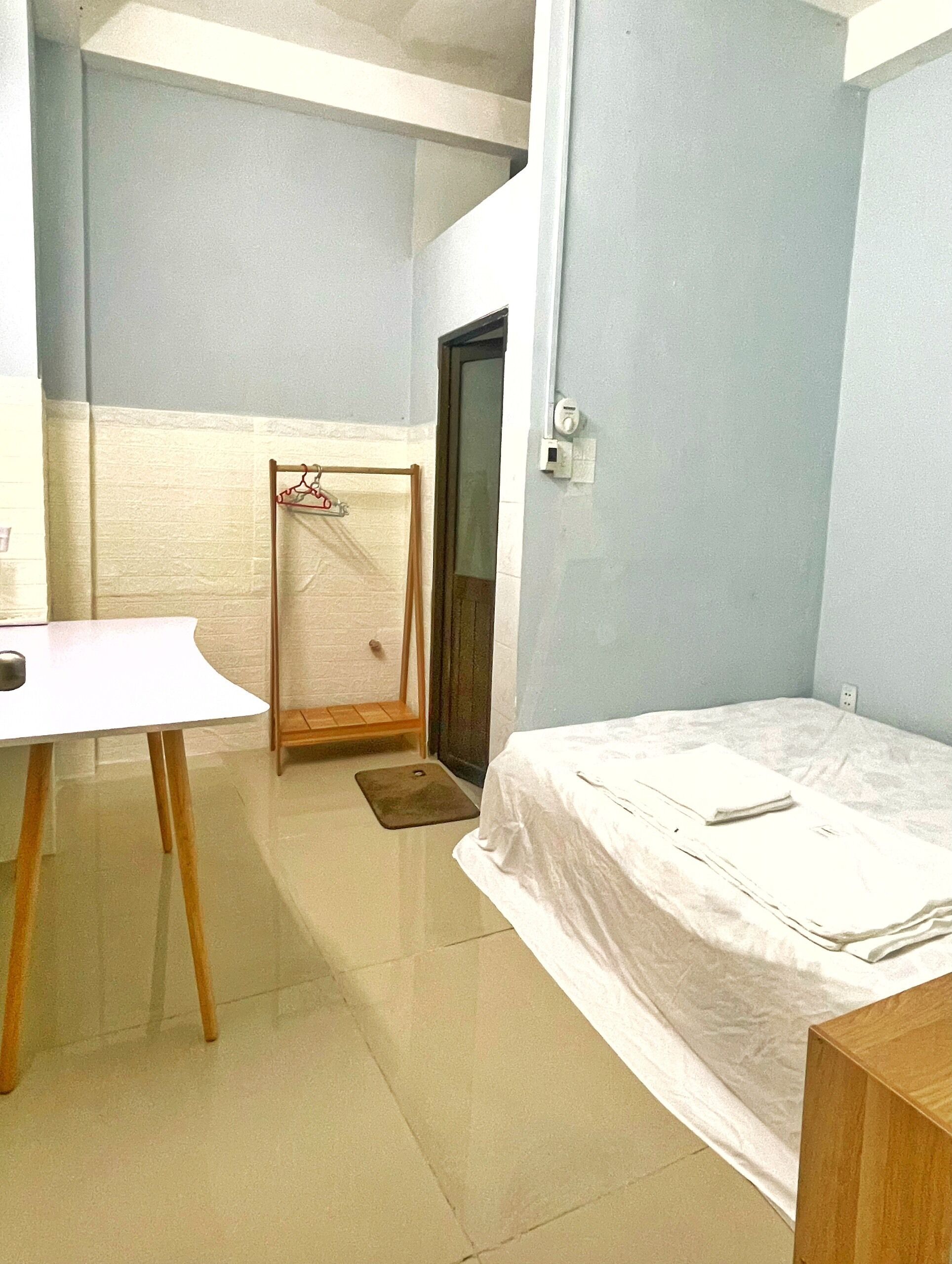 A small, clean room with a bed, a desk, and a door.